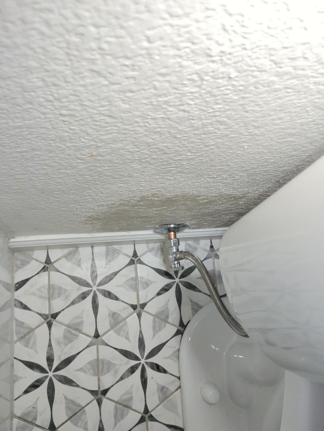 Indoor water staining on the ceiling above the toilet — related leak damage