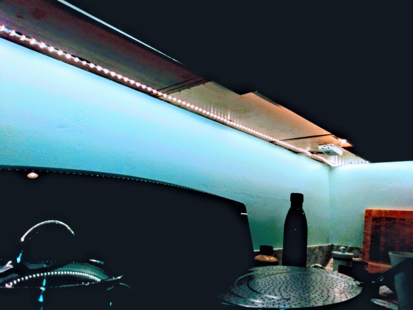 Night view: low-voltage LED strip under the cabinets illuminates the wall and counter area with even cool-white light.